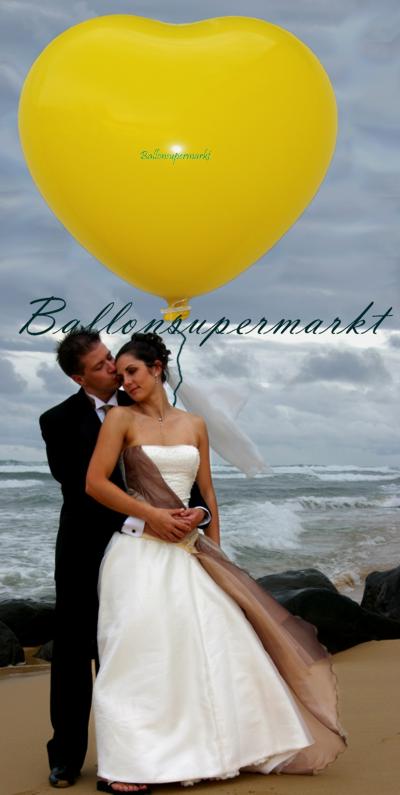 Gelber Riesen-Herzluftballon mit Hochzeitspaar am Strand